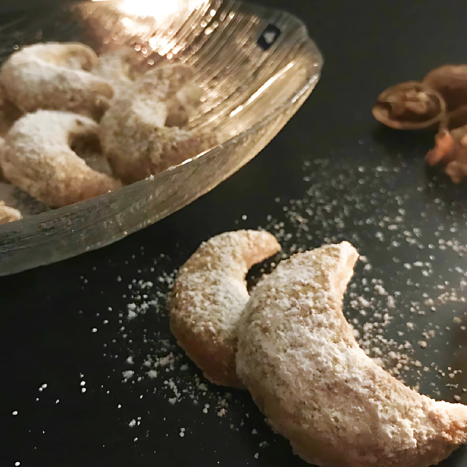 Mit Puderzucker bestäubte Vanillekipferl in einer Glasschale serviert.