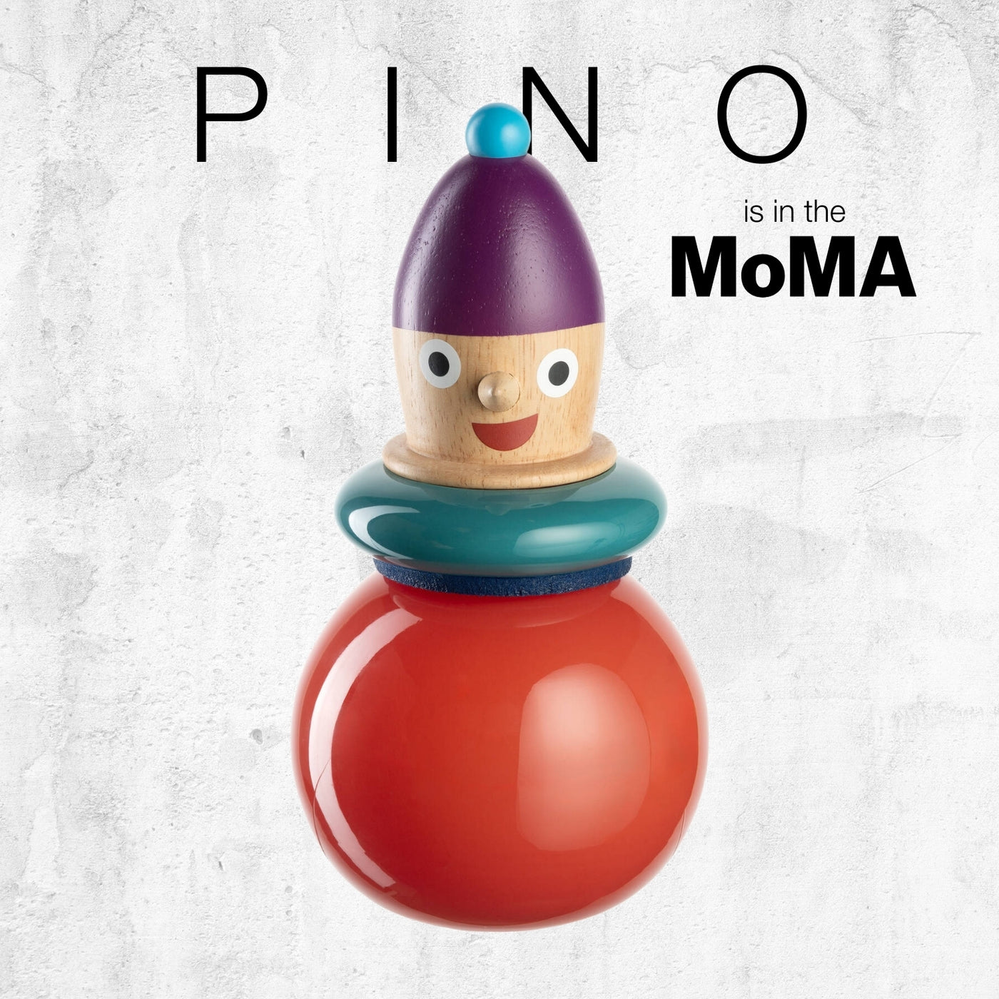 Stapelbare Figur mit violetter Mütze, fröhlichem Gesicht und großer roter Kugelbasis. Text: „PINO is in the MoMA“.