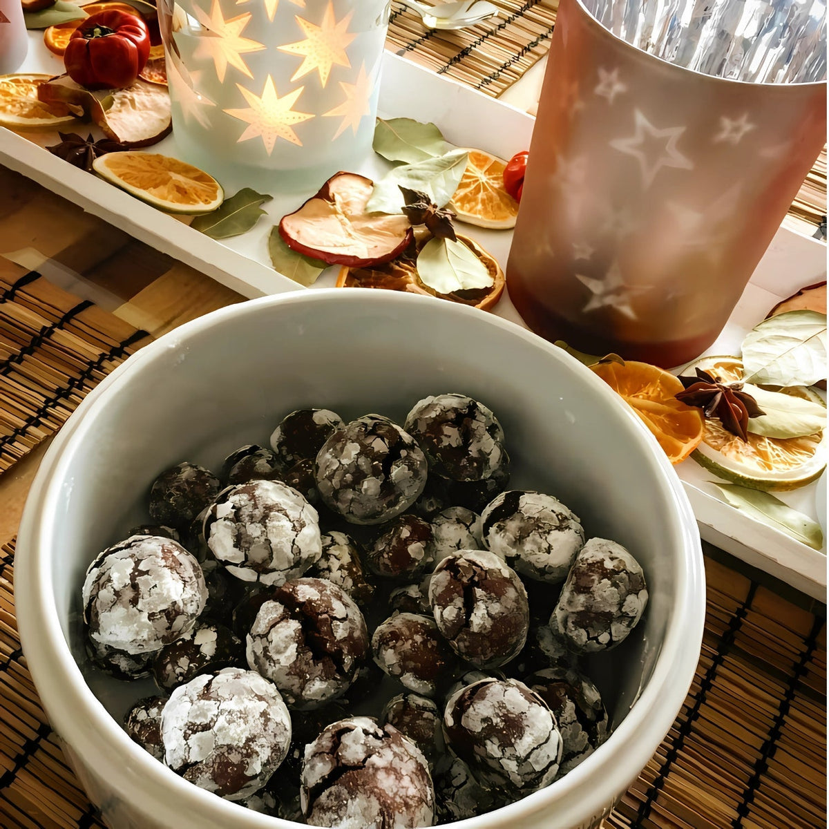 Crinkle-Cookies mit Puderzucker in einer weißen Schale – stimmungsvolle Adventsdeko im Hintergrund.