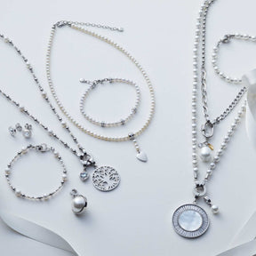 Schmuckkollektion mit Perlenketten, Armbändern und Anhängern in Weiß auf hellem Hintergrund