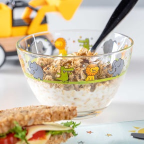 Schale BAMBINI gefüllt mit Müsli und Milch, daneben belegtes Brötchen, Frühstückstisch