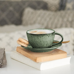 Keramiktasse MATERA grün auf Bücherstapel mit Macaron und Kaffee