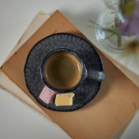 Keramikuntertasse MATERA anthrazit mit Espressotasse, Macarons und Blumenvase auf Papier
