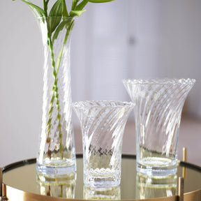 Vase RAVENNA mit Blumen auf Glastisch, zwei leere Gläser daneben
