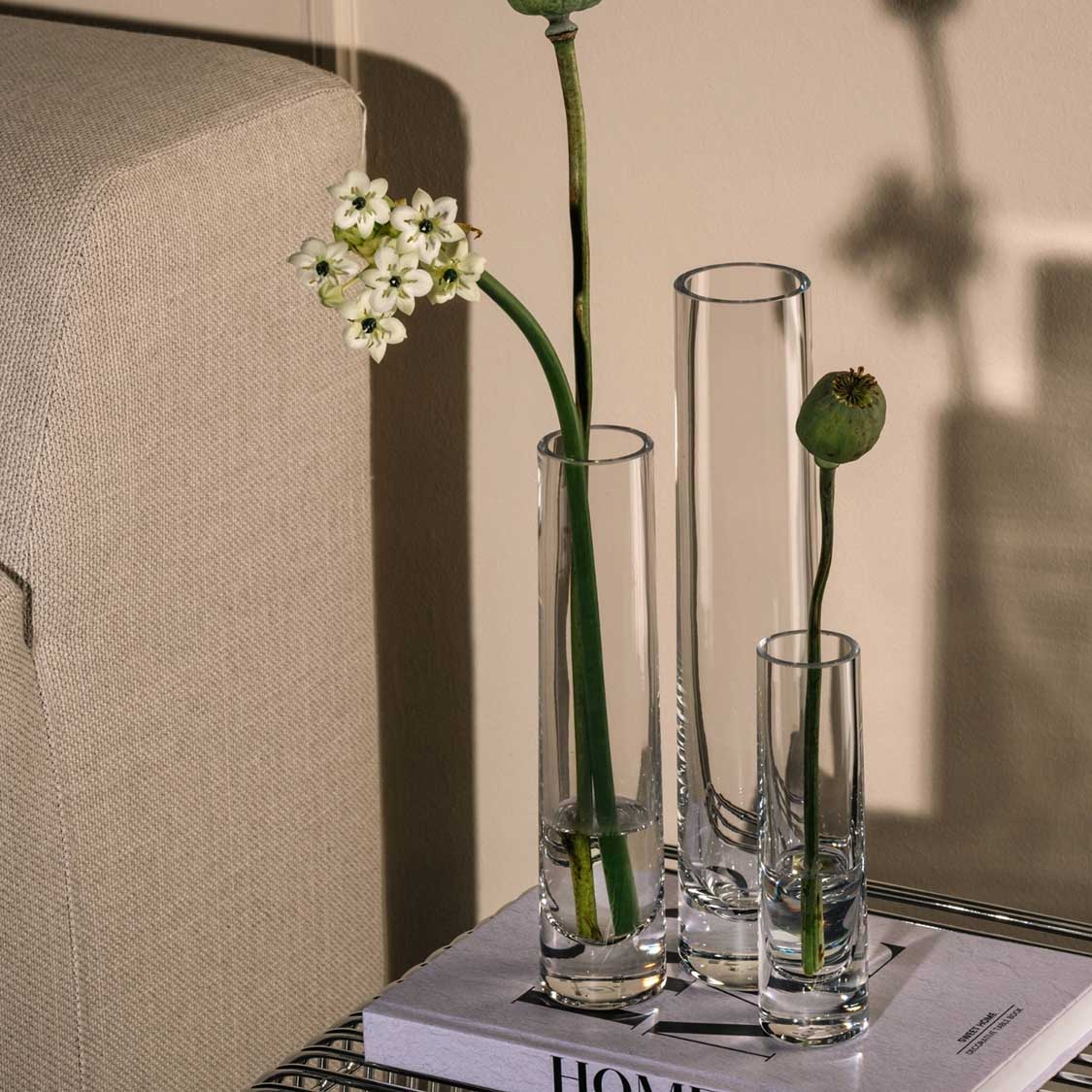Solifleurvase NOVARA mit weißen Blüten und grünen Stielen auf Zeitschrift, Wohnraum