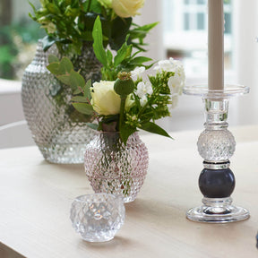 Tischvase POESIA viola mit weißen Blüten auf Couchtisch neben Kerzenständer