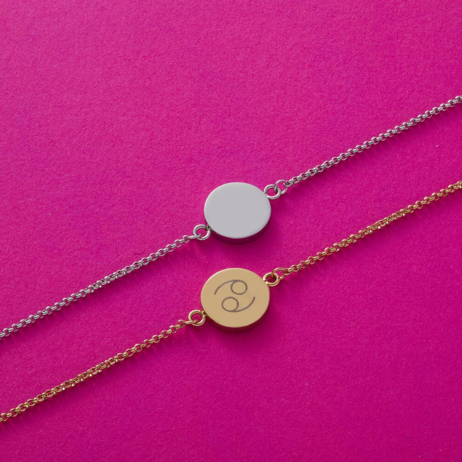 Zwei Armbänder MARLA auf pinkem Hintergrund, eines silber mit leerem Plakette, eines gold mit Gravur