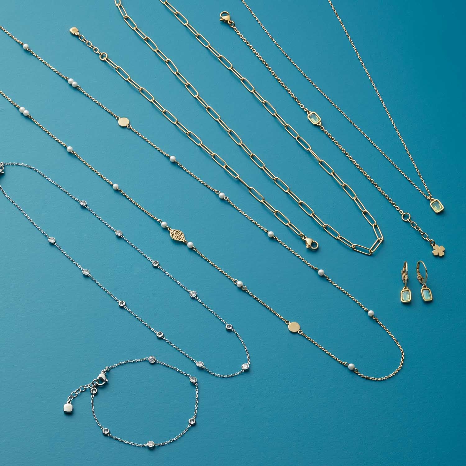 Schmuckkollektion mit Halsketten, Armband und Ohrringen aus Glas auf blauem Hintergrund