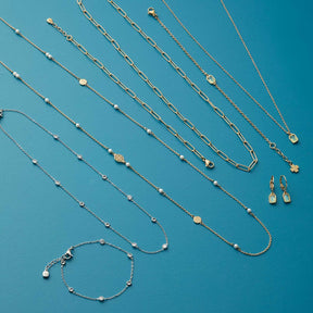 Schmuckkollektion mit Halsketten, Armband und Ohrringen aus Glas auf blauem Hintergrund