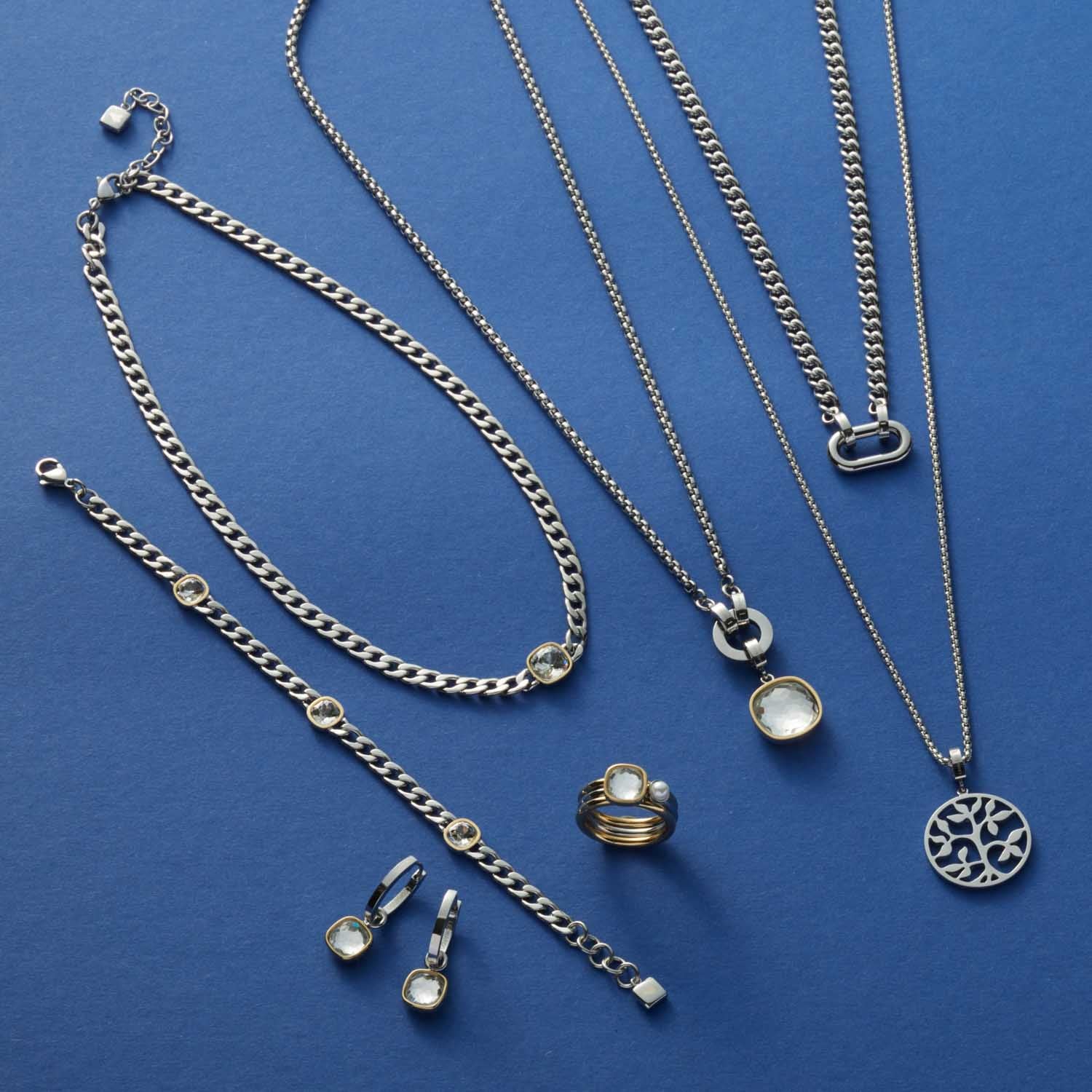 Silberner Schmuck der Serie BEAUTY'S auf blauem Hintergrund, Ketten, Ohrringe und Ring