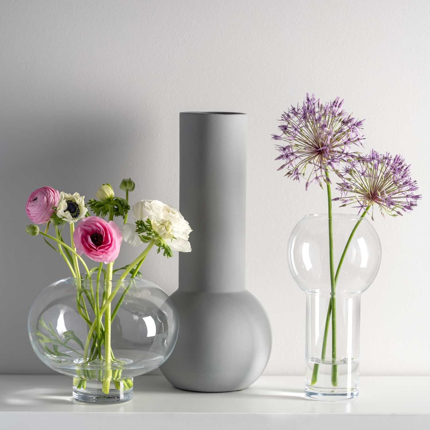Vase VERNAZZO 27 cm aus Glas mit Blumenarrangements auf weißer Oberfläche