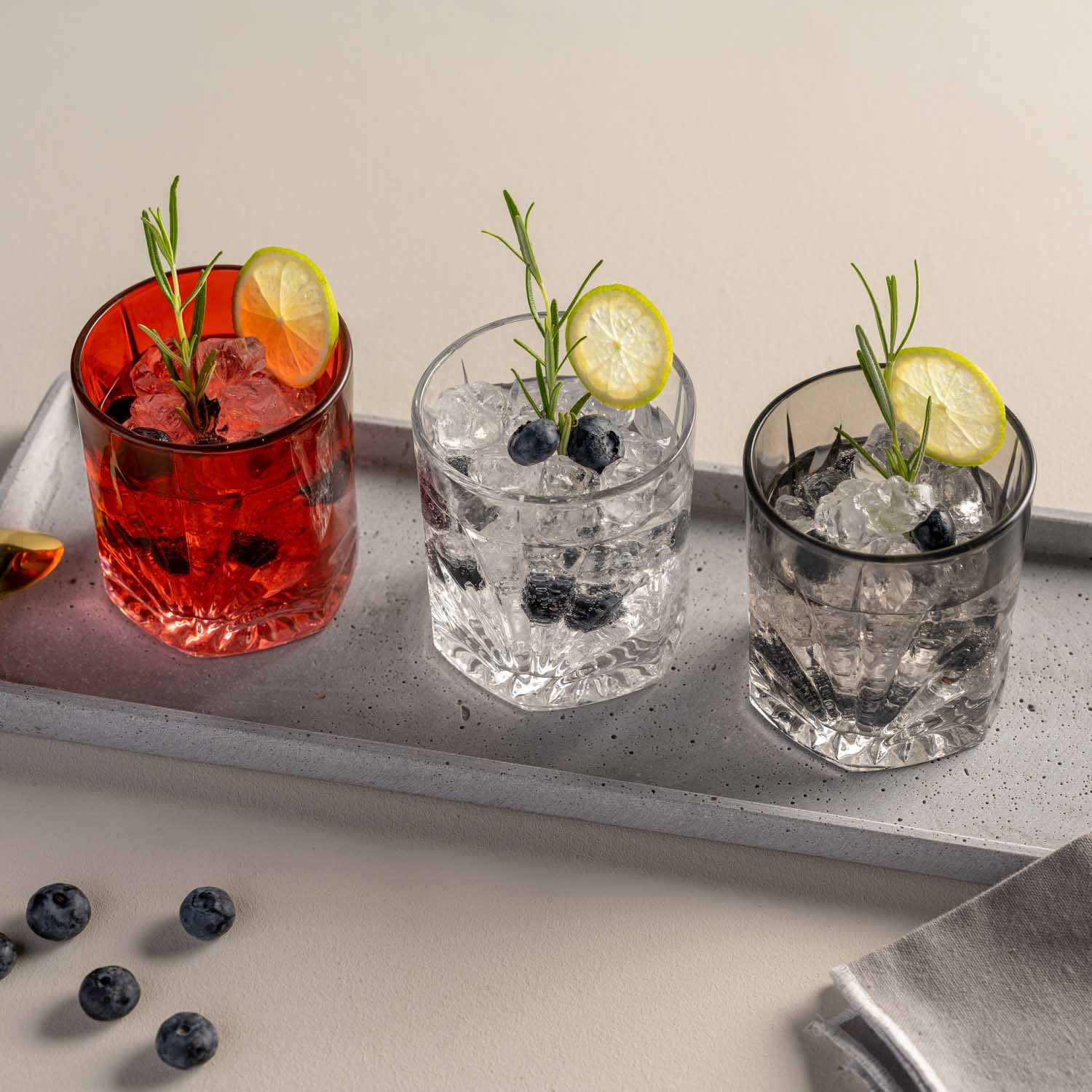 Trinkglas CAPRI mit Cocktails, Blaubeeren, Zitronenscheiben und Rosmarinzweigen auf Tablett