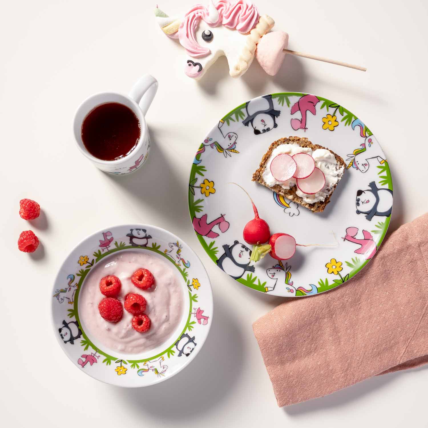 Kindergeschirr BAMBINI mit Panda- und Flamingo-Motiven, gedeckter Tisch mit Joghurt, Toast, Getränk und Süßigkeiten