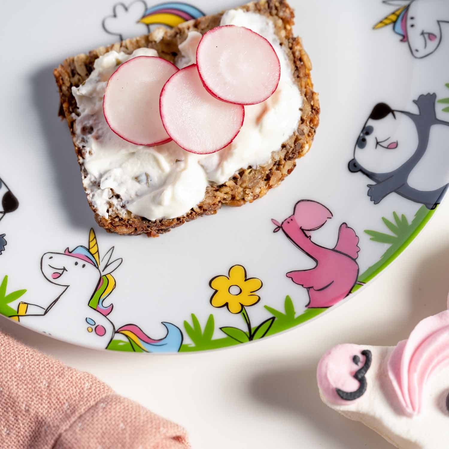 Kindergeschirr BAMBINI mit Einhorn- und Tiermotiven, belegtes Brot mit Frischkäse und Radieschen