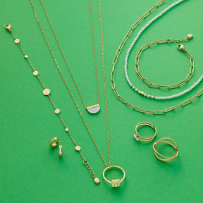 Goldene Halsketten und Ringe mit Glasperlen auf grünem Hintergrund