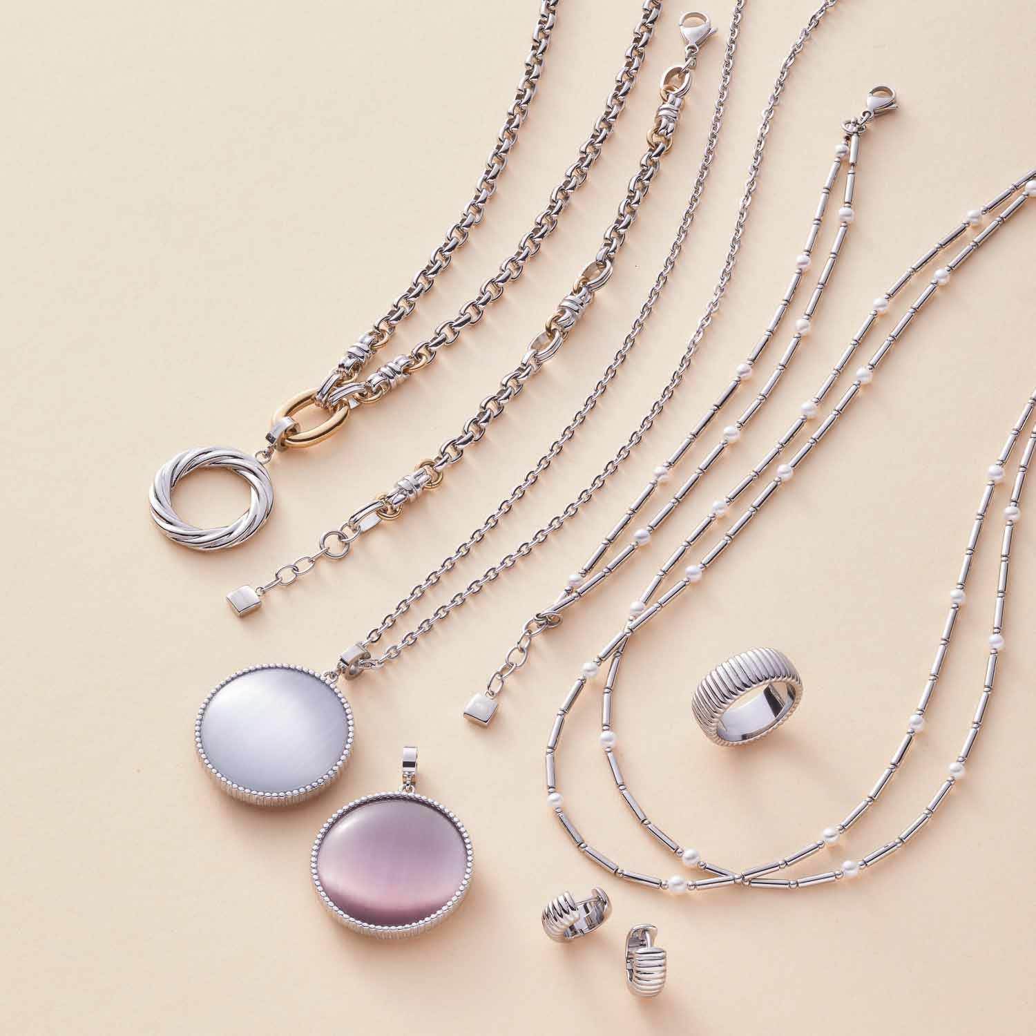 Schmuckkollektion der Serie MIRELLA mit Ketten, Ringen und Anhängern aus Edelstahl und Perlmutt auf beigem Hintergrund