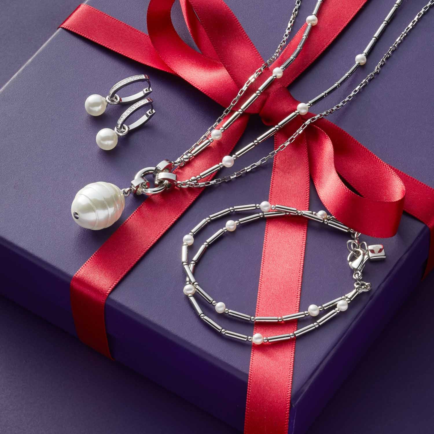Armband MIRELLA mit Ohrringstecker und Halskette auf violetter Geschenkbox mit rotem Band