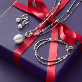 Armband MIRELLA mit Ohrringstecker und Halskette auf violetter Geschenkbox mit rotem Band