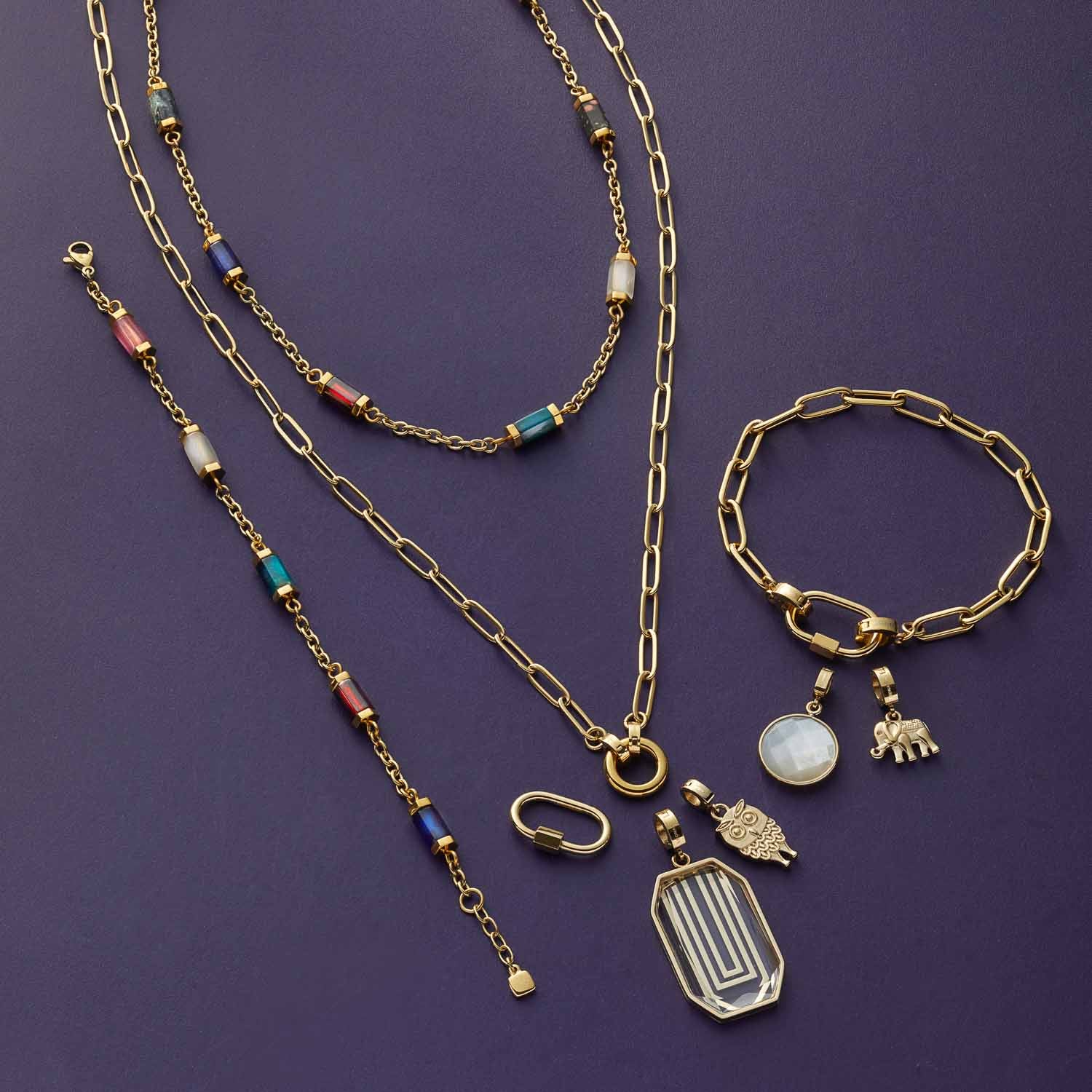 Halskette MODA mit Anhängern, Armband und Charms aus gold auf violettem Hintergrund
