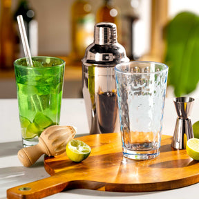 Cocktail-Szene mit Trinkgläsern, Cocktail-Shaker und Zitrusfrüchten auf Holzbrett