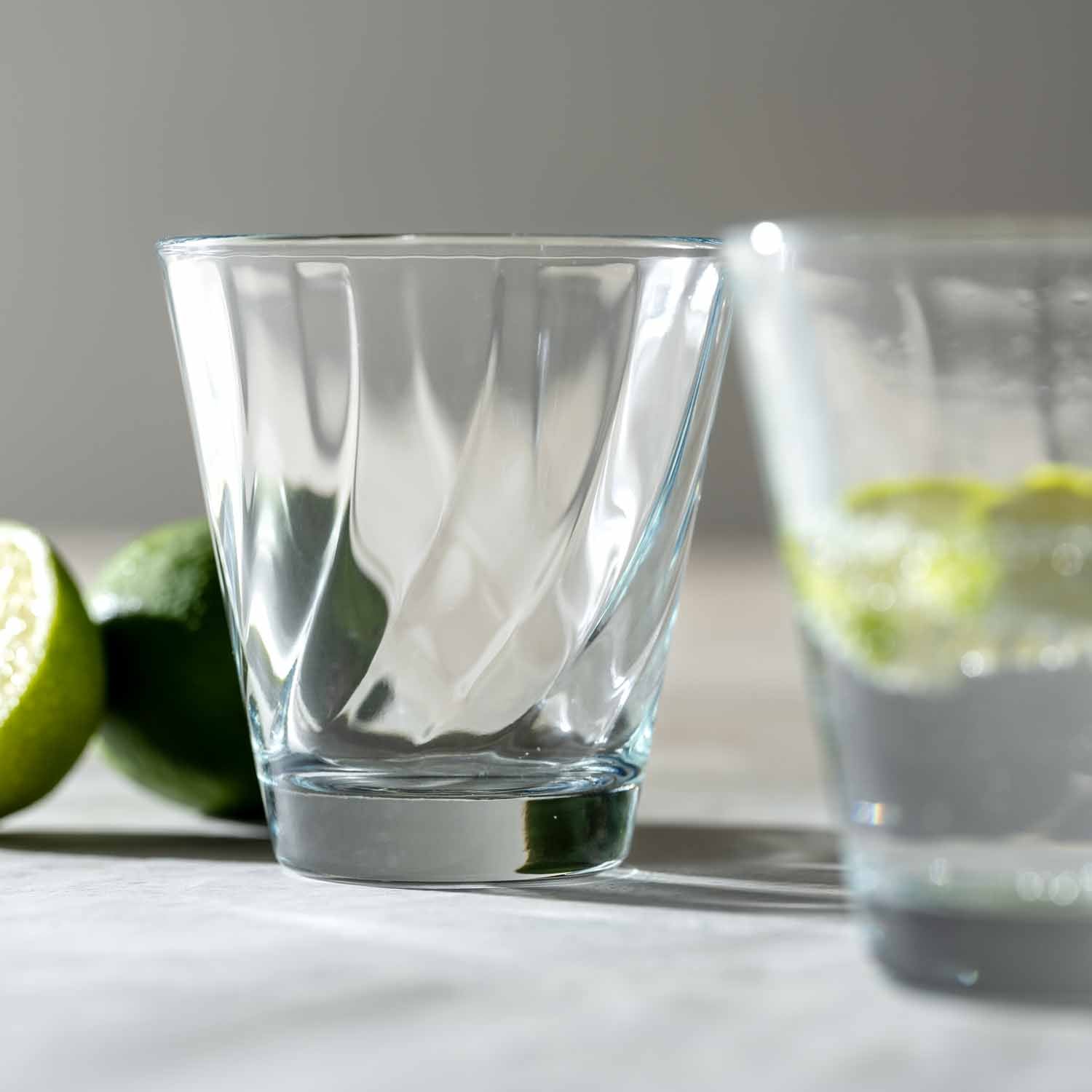 Trinkglas TWIST 215 ml mit Limettenscheiben auf weißer Oberfläche