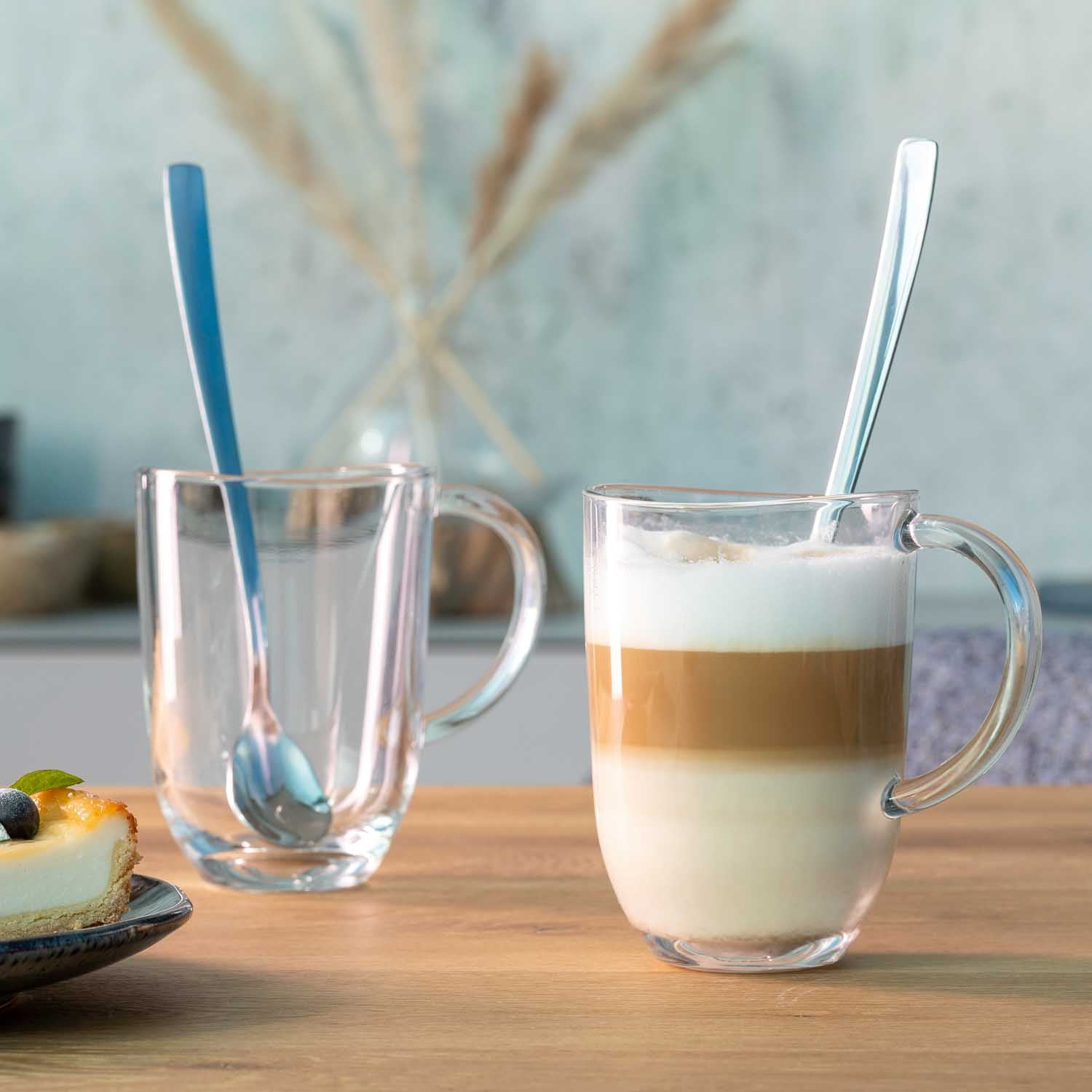 Zwei Latte Macchiato Tassen NAPOLI mit Löffeln auf Holztisch, eine gefüllt, eine leer
