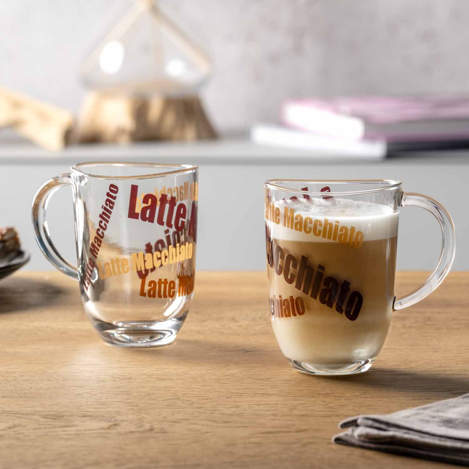 Zwei gefüllte Latte Macchiato Tassen NAPOLI mit roter Beschriftung auf Holztisch