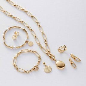 Goldenes Schmuckset mit Kette, Armbändern, Ringen und Anhängern auf weißem Untergrund