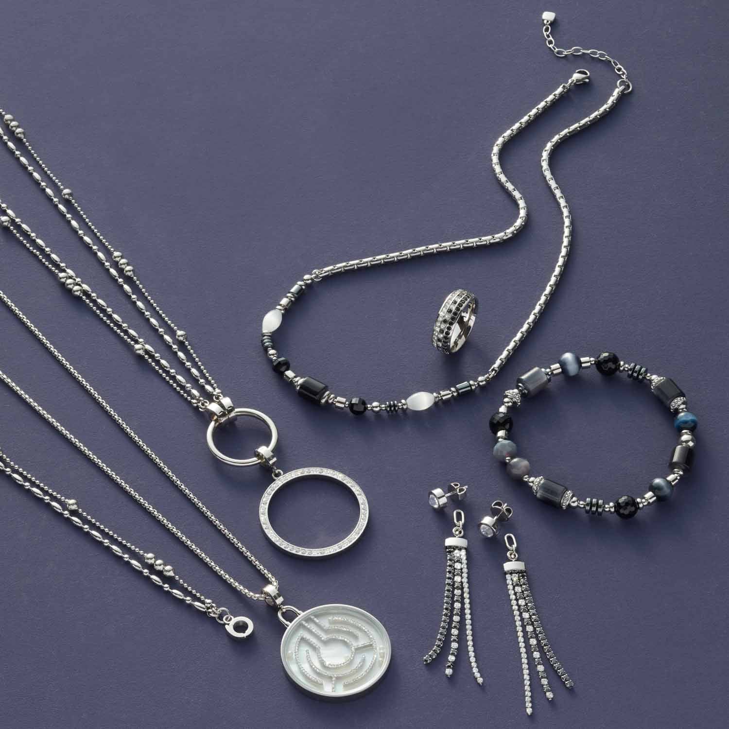 Silberner Schmuckset mit Halsketten, Armband, Ring und Ohrhänger auf violettem Hintergrund