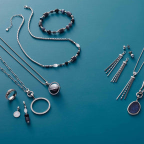 Schmuckkollektion mit Armband CASORIA silber und weiteren Schmuckstücken auf blauem Hintergrund