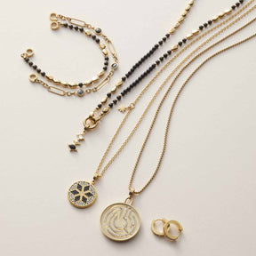 Creole INKA NERO gold, Armband, Halsketten und Ringe auf hellem Untergrund