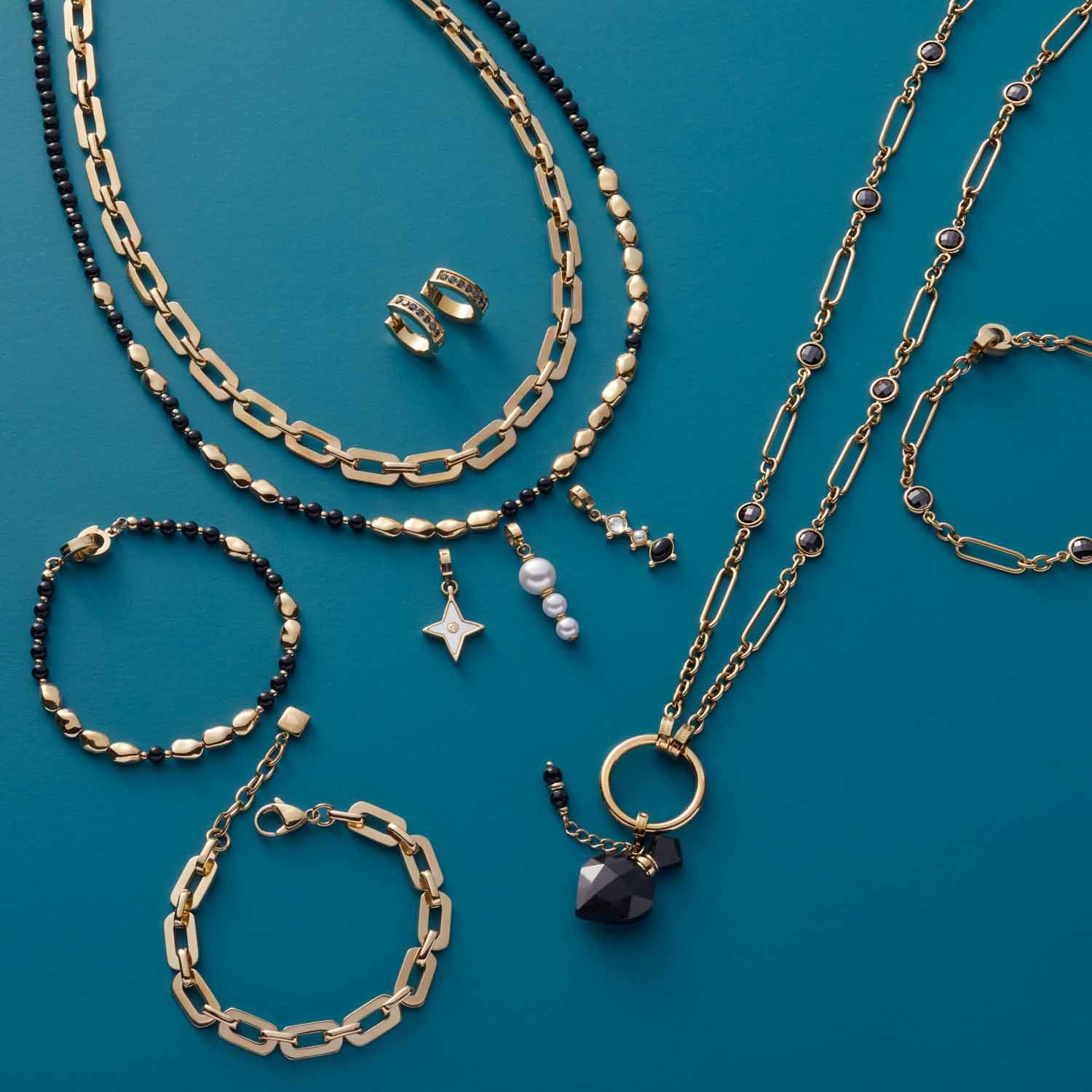 Schmuckkollektion mit Creole, Ketten, Armbändern und Ringen auf türkisblauem Hintergrund
