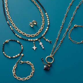 Schmuckkollektion mit Creole, Ketten, Armbändern und Ringen auf türkisblauem Hintergrund