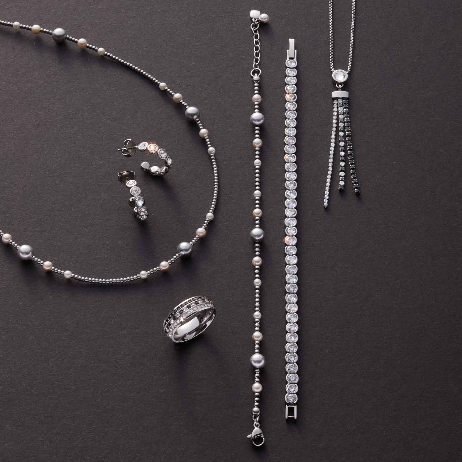 Schmuckkollektion mit Ring ATURA 19, Halsketten, Armband und Ohrringe aus Glas auf grauem Hintergrund