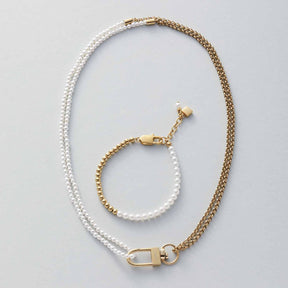 Halskette LUCINDA mit Perlen und Goldkugeln, dazu passendes Armband auf grauem Hintergrund