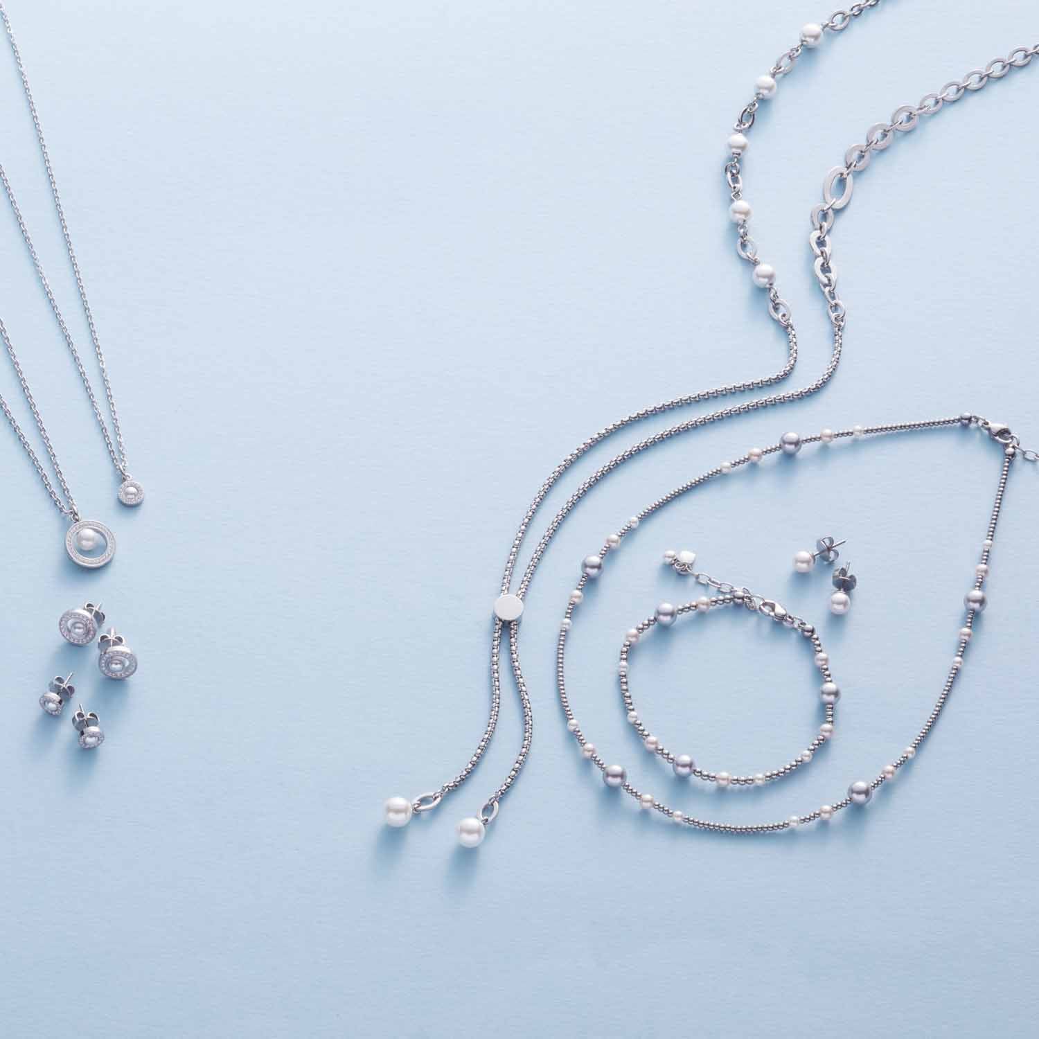 Silberne Schmuckkollektion ELSANA mit Armbändern, Ketten und Perlenanhängern auf hellem Hintergrund