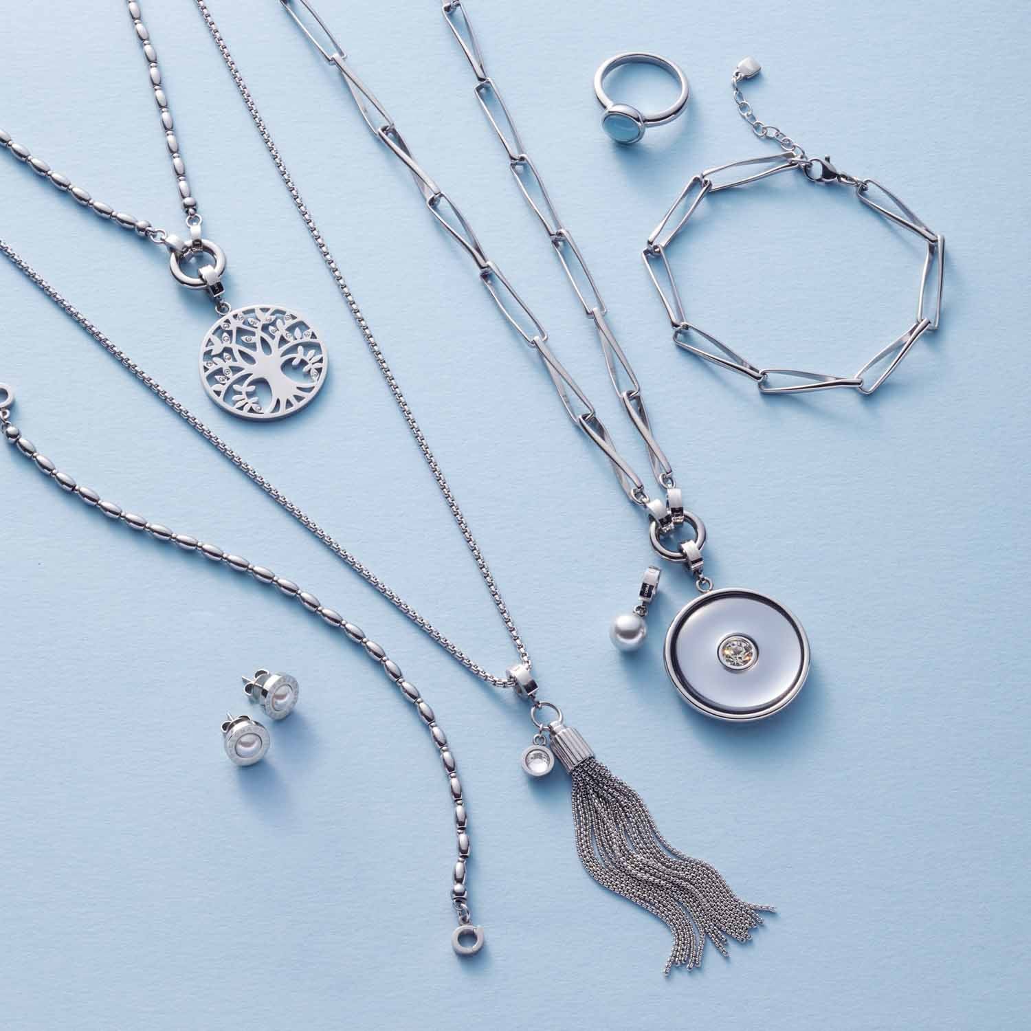 Silberschmuck-Kollektion mit Halsketten, Ringen und Armband auf hellblauem Hintergrund