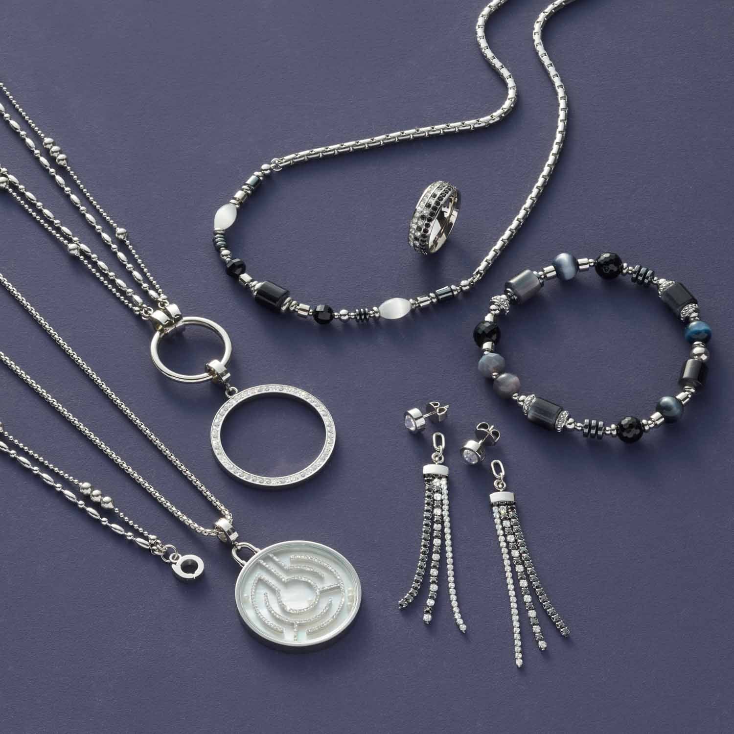 Silberschmuck-Set mit Halsketten, Ring, Armband und Ohrringen auf grauem Untergrund