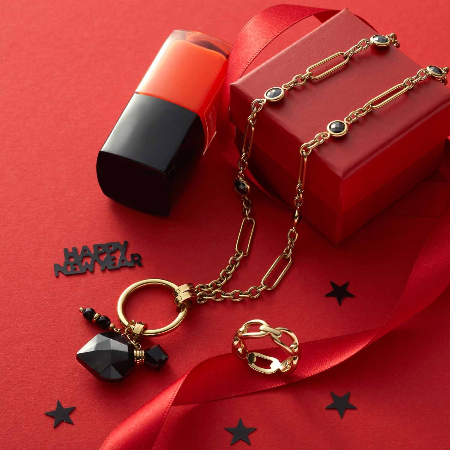 Halskette DELICA mit Glaspendant auf rotem Hintergrund, Lippenstift und Geschenkbox