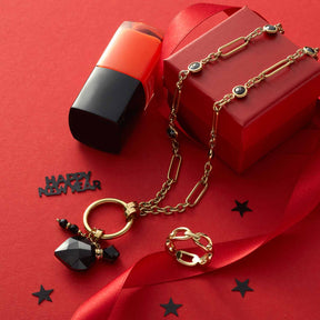 Halskette DELICA mit Glaspendant auf rotem Hintergrund, Lippenstift und Geschenkbox