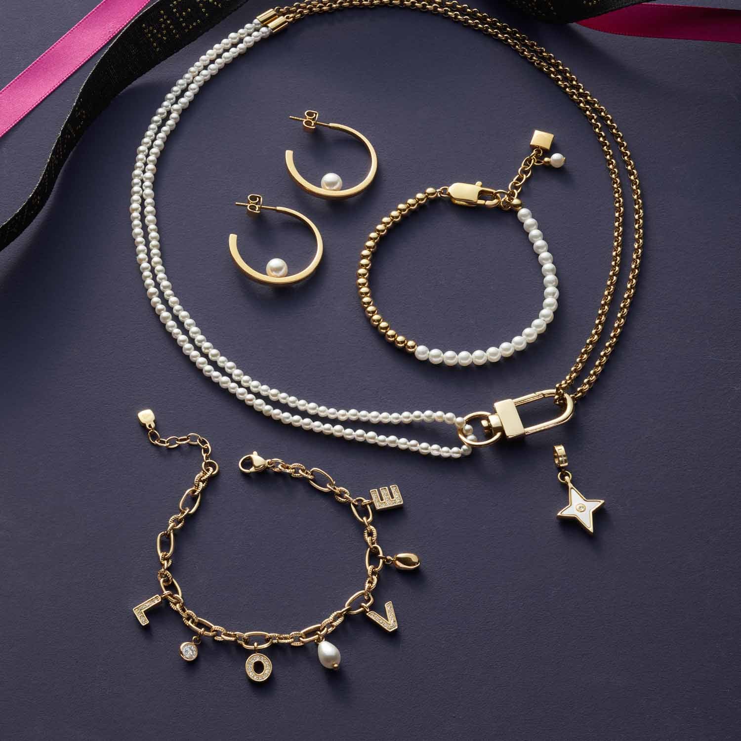 Schmuckkollektion mit goldenem Armband, Ohringen, Halskette und Perlenarmband auf grauem Untergrund