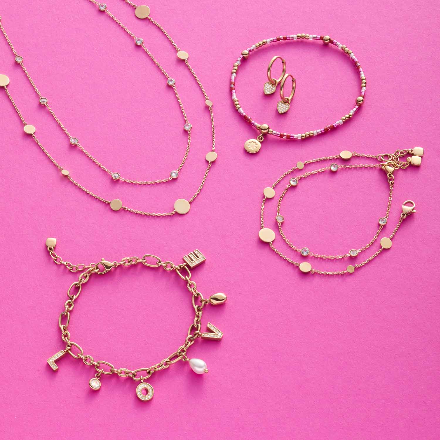 Goldschmuck-Set mit Armbändern und Halsketten auf rosa Hintergrund