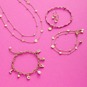 Goldschmuck-Set mit Armbändern und Halsketten auf rosa Hintergrund