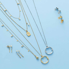 Halskette CAMPAGNOLA mit Anhängern und passende Ohrringe in Gold und Silber auf blauem Hintergrund
