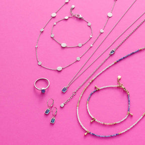 Schmuckkollektion auf rosa Hintergrund: Armbänder, Ketten und Ring mit Perlen, Sodalith und Muscheln
