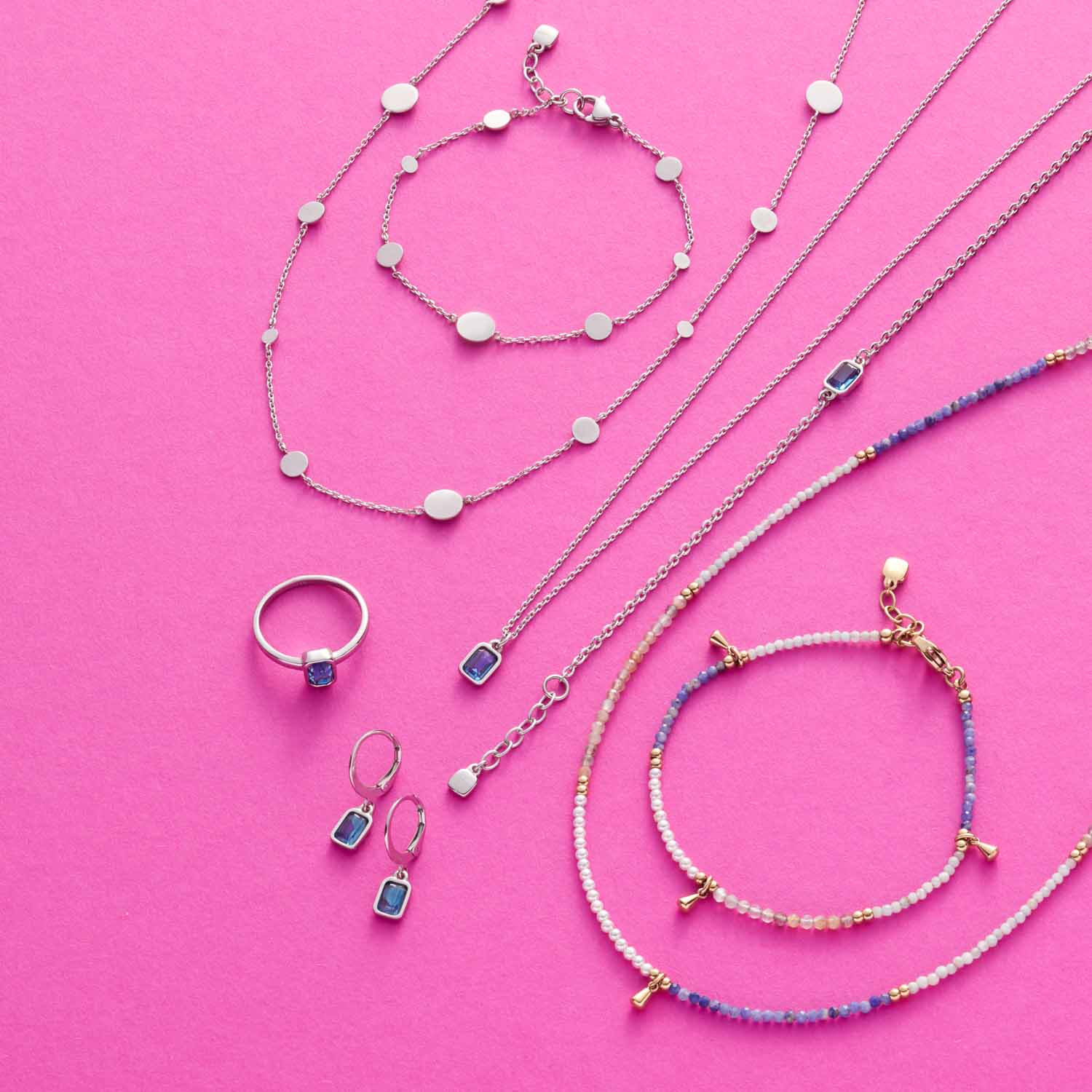 Schmuckkollektion mit Ringen, Halsketten und Armbändern aus Glas auf rosa Hintergrund