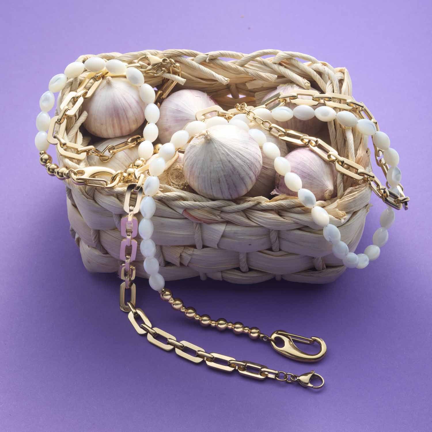 Halskette PATSY mit goldener Kette, Muscheln und Perlen auf violettem Hintergrund