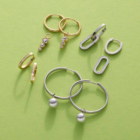 Schmuckkollektion auf gelb-grünem Hintergrund, Gold- und Silberringe mit Perlen und Zirkonia