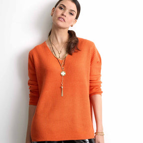 Frau trägt oranges Rippenstrick-Shirt und goldenes Armband TORY