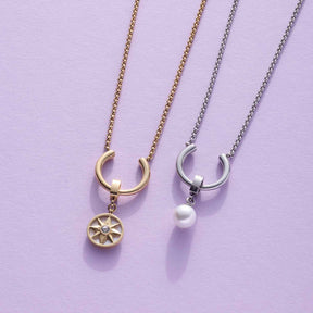Zwei Halsketten MAISY mit Clip-Verschluss, eine mit Sonnenscharm, eine mit Perlenanhänger auf violettem Hintergrund